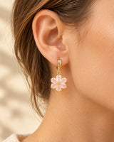 Gold-tone mini hoop with a pale-pink six-petal flower drop worn on an ear