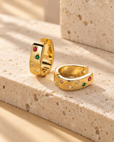 Gold-tone mini huggie hoop with multicolor square zircon stones on textured warm stone