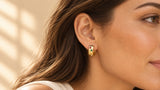 Gold-tone mini huggie hoop with multicolor square zircon stones worn on an ear, film still