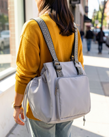 Gray drawstring pocket tote worn as a backpack on a city sidewalk