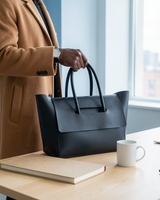 Black structured flap tote set down on an office desk