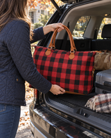 Red buffalo check weekender bag lifted into an SUV trunk for a trip