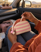 Pink striped canvas pouch opened on a lap during a road trip