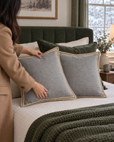 Gray linen pillow covers with jute trim on a made bed on a snowy morning