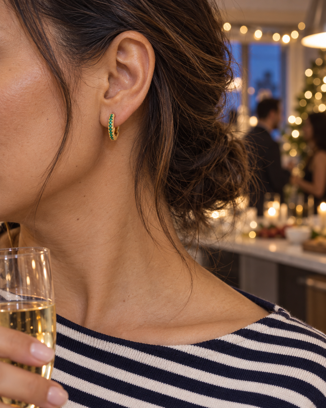 Gold-tone green stone mini hoop earrings worn at a holiday party
