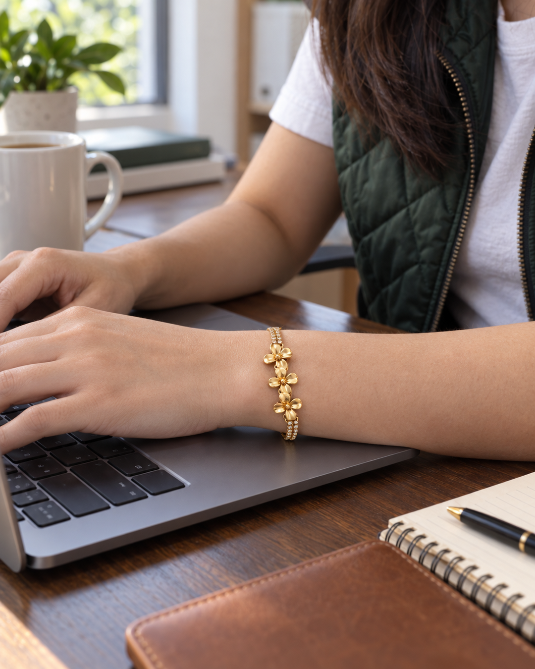 Gold-tone flower bracelet worn at a laptop at the office