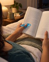 Blue resin thumb page holder holding a book open in bed at night