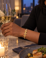 Gold-tone flower bracelet worn at an evening dinner table
