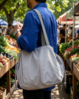 Gray drawstring pocket tote carried on the shoulder at a farmers market
