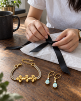 Gold-tone flower bracelet and opal-look teardrop earrings wrapped with tissue paper and a satin ribbon