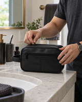 Black faux leather dopp kit zipped closed on a bathroom counter