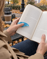 Blue resin thumb page holder holding a book open on a park bench