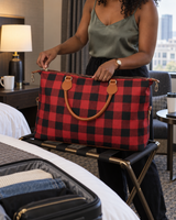 Red buffalo check weekender bag unzipped on a hotel luggage rack