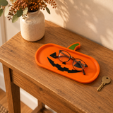 Orange pumpkin tray on a wooden entryway table, with glasses resting in the well and a key beside it